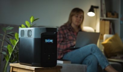 Young,Woman,Uses,Portable,Power,Station,To,Charge,Her,Laptop